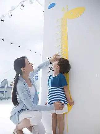 青年女人在为 i>小 /i> i>男 /i> i>孩 /i>测量身高