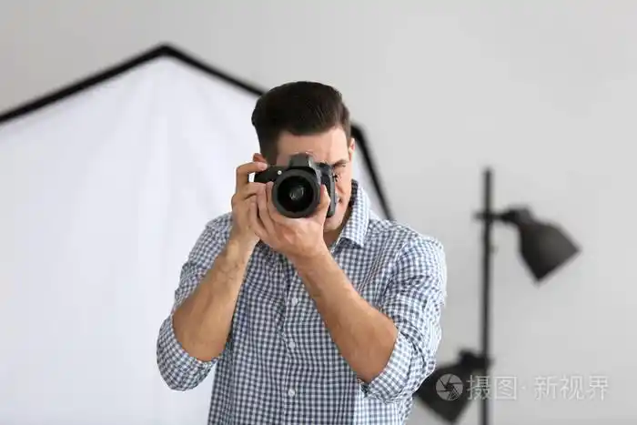 年轻摄影师在专业工作室拍照照片-正版商用图片03ckut-摄图新视界