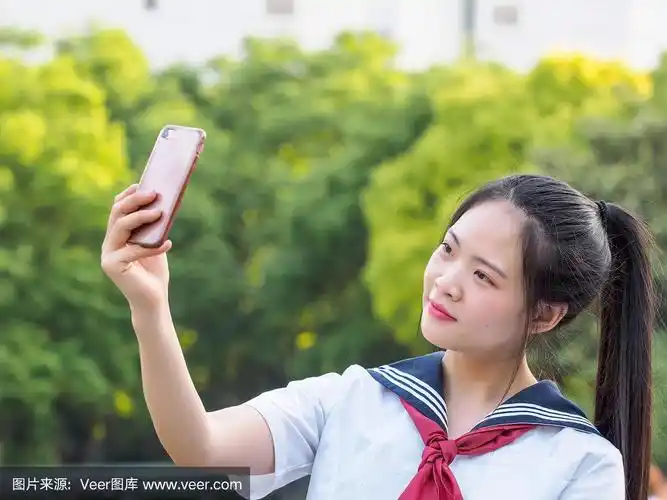 中国女学生穿着校服,用智能手机自拍.