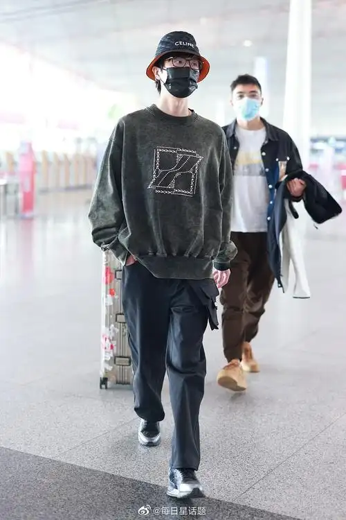 2022年4月9日,北京,许嵩穿墨绿色卫衣戴celine渔夫帽现身机场,帅气