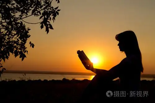 一个女孩在日落时阅读的剪影