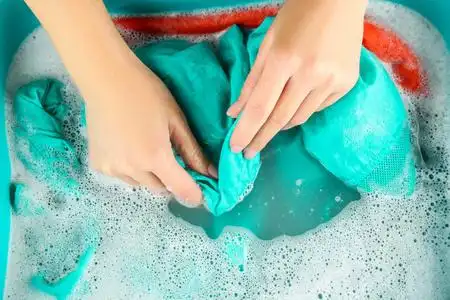 洗涤剂中洗白色毛衣衣服洗手池中的女性手洗彩色衣服女性手洗衣服特写