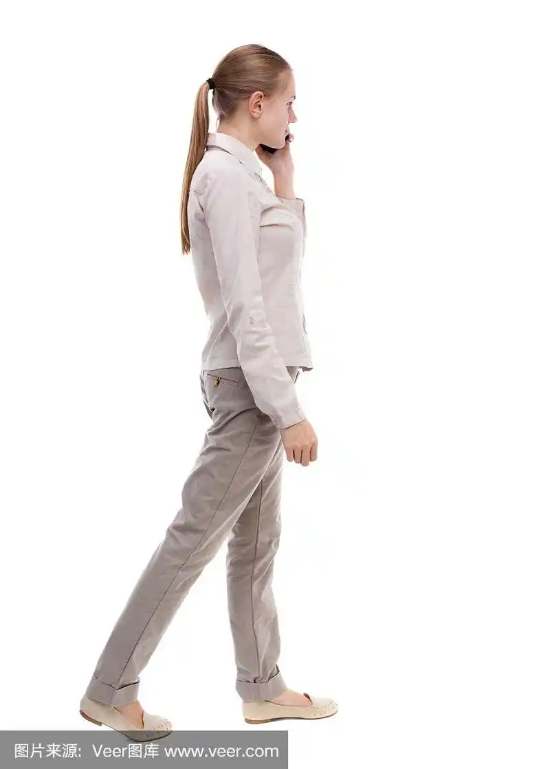 一个拿着手机走路的女人的侧视图.