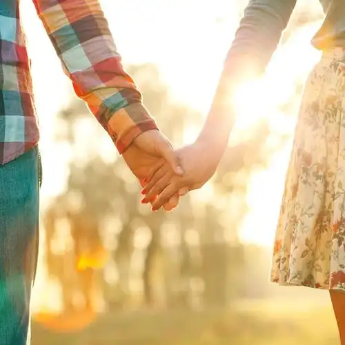 海滩日落下的情侣手牵手