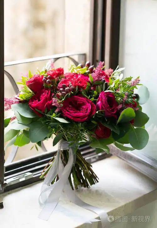明亮的红色婚礼花束鲜花和桉树站在窗台上