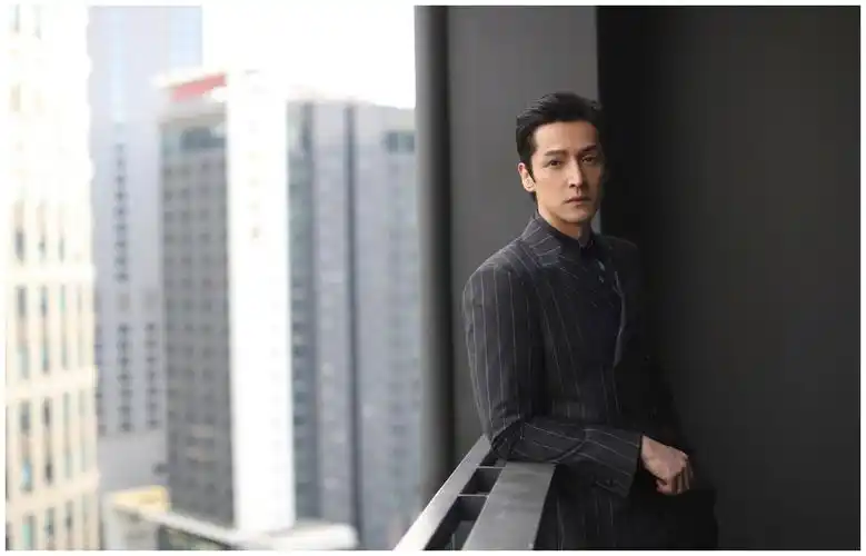 胡歌身穿深色条纹西服出席活动,清爽干练