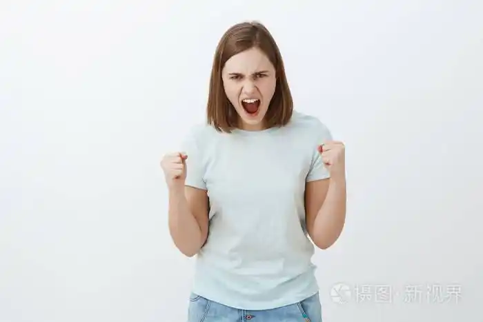 的画像从前额皱起眉头和生气地握紧拳头从怒火和 fure 在灰墙上发脾气