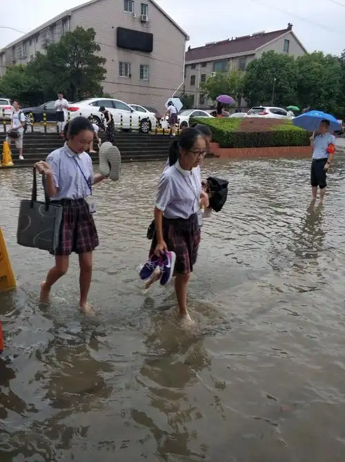 由于道路严重积水,师生们克服困难,赤脚进学校.