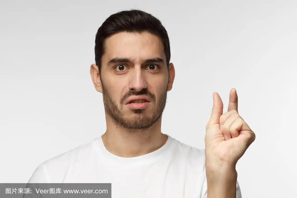 穿着白色t恤的年轻人,用手比划着,露出小小的尺寸,脸上带着不悦的表情