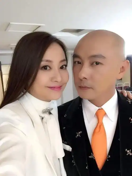 张卫健老婆真贵气,身披白西装手拎爱马仕,比老公的大光头还抢镜