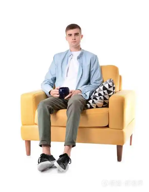 一个年轻人端着一杯咖啡坐在白色背景的扶手椅上