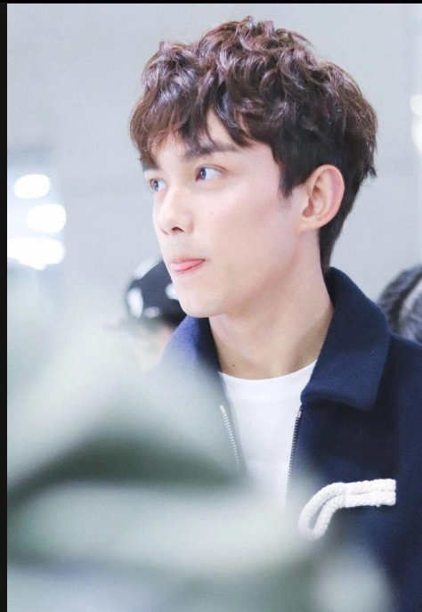 吴磊穿深蓝色外套内搭白t现身机场 抿嘴卖萌行走间气场十足