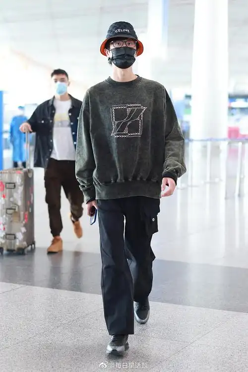 2022年4月9日,北京,许嵩穿墨绿色卫衣戴celine渔夫帽现身机场,帅气