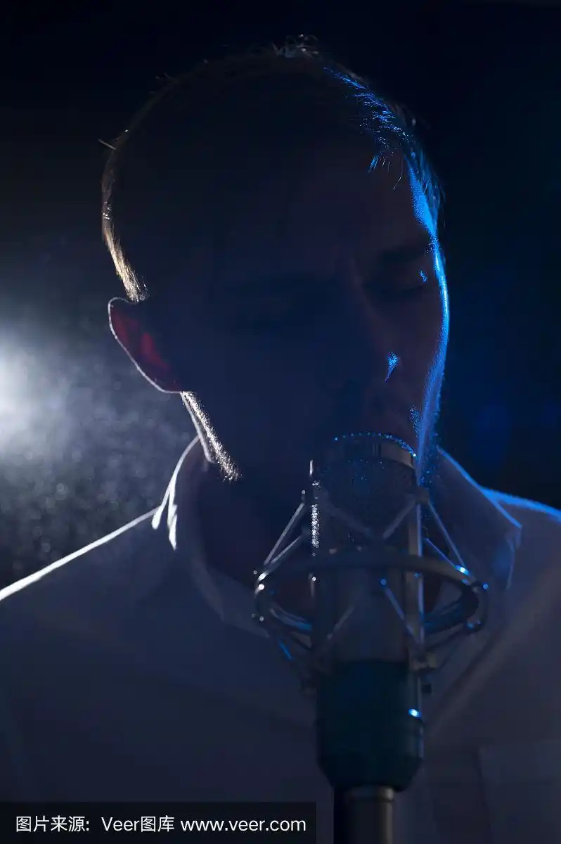 可爱的男歌手拿着麦克风在舞台上