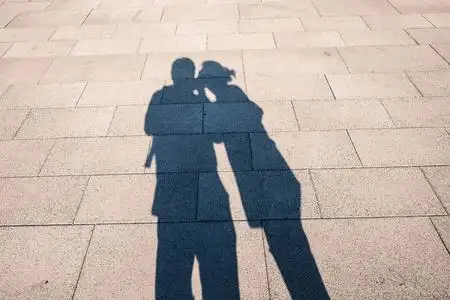 秋天的城市公园里,年轻浪漫的情侣的影子,男人拥抱着在树上互相看着