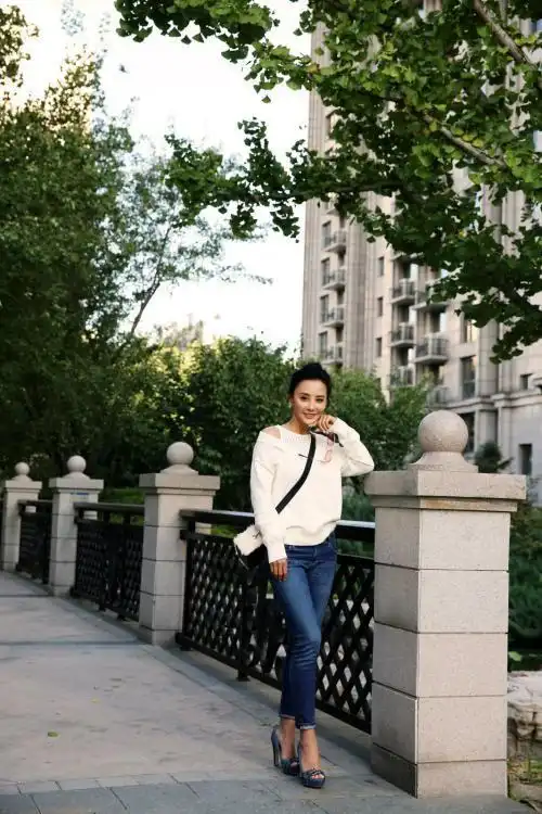 下图照片中,马雅舒穿了一件米白色小露肩上衣搭配深色牛仔紧身裤,修饰