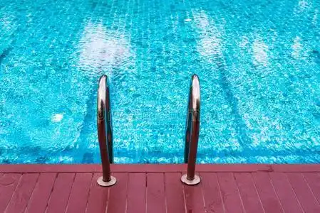 钢梯子和蓝色游泳水池和红色的木制的地面照片
