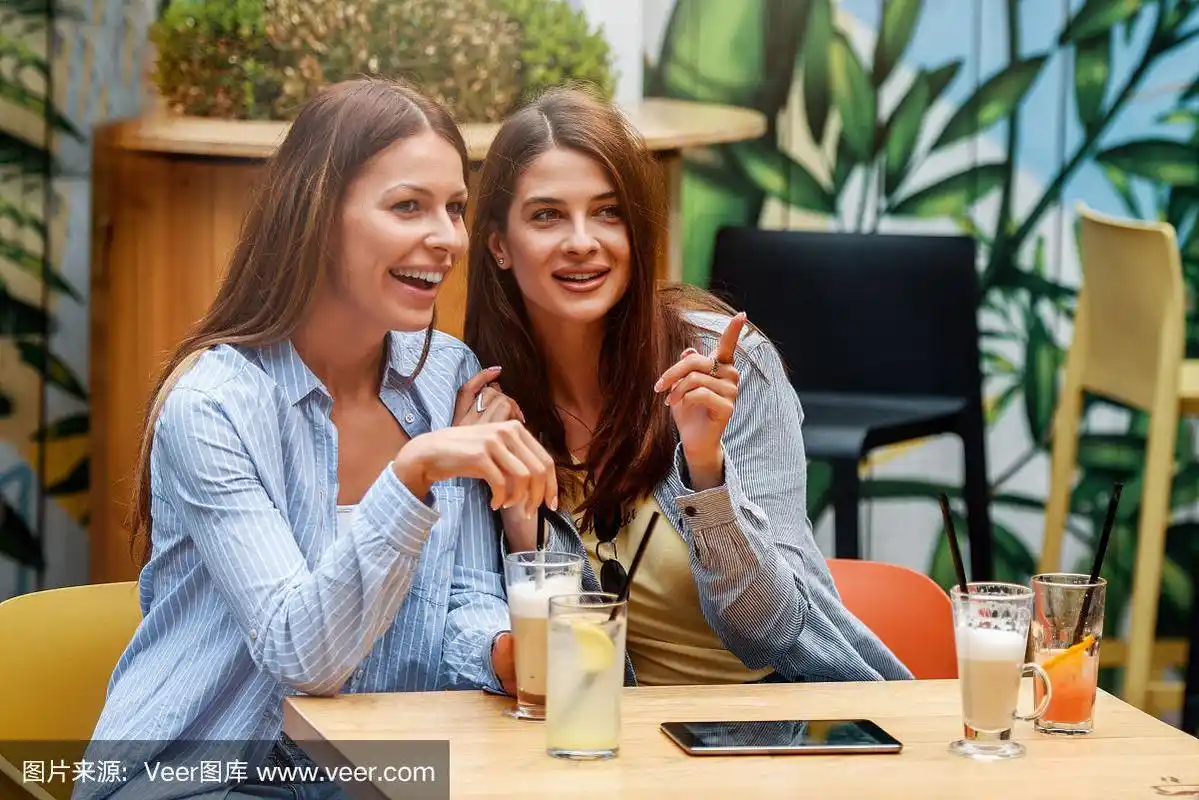 女孩谈话.两个女性朋友在咖啡店聊天,玩得很开心