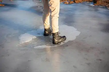 冬天穿军靴.一个女孩站在冰上.照片