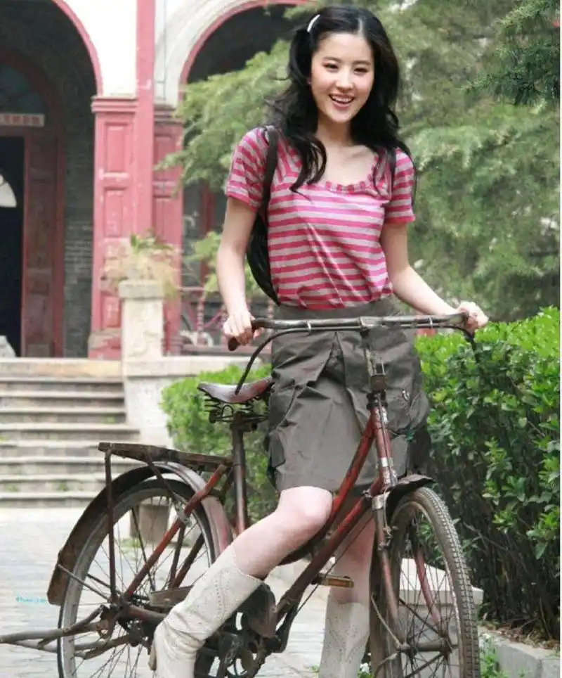 刘亦菲骑自行车的老照片,穿着条纹短袖和灰色裙子,造型满满的都是回忆