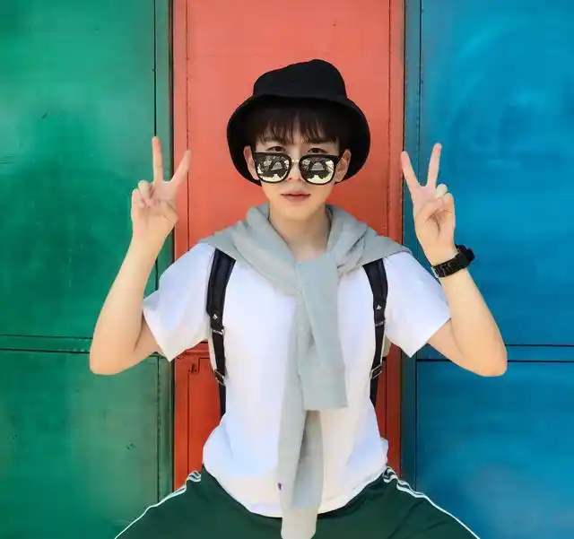 费启鸣晒生活照,穿着紫色短袖和灰色长裤对镜头比耶,可爱大方