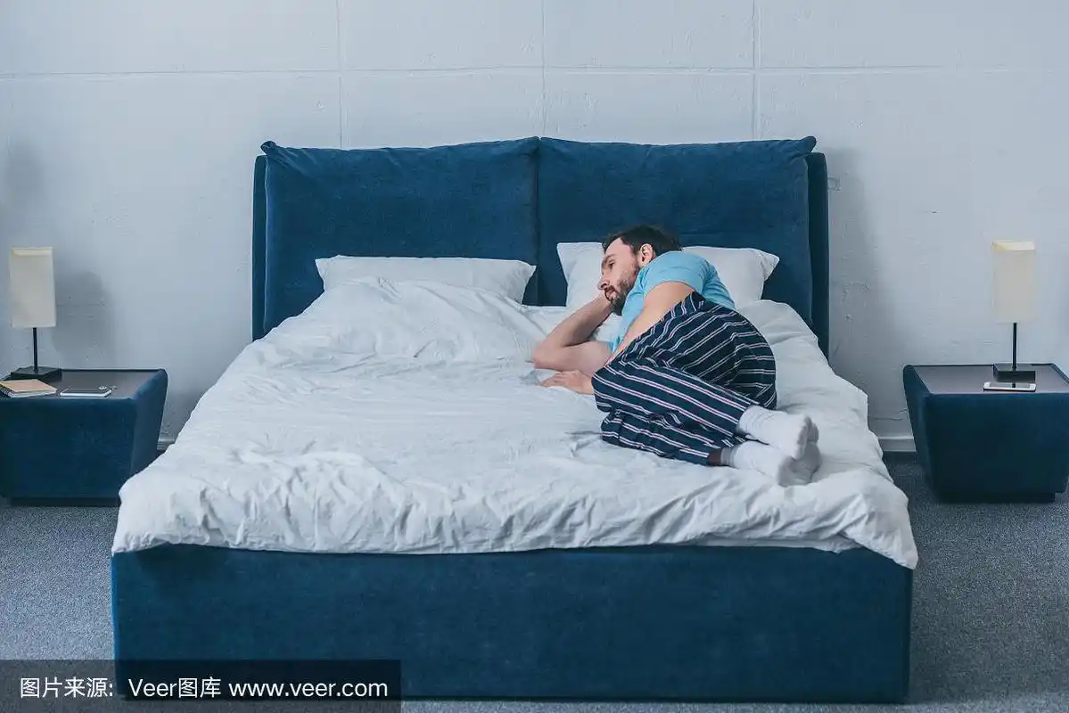 伤心孤独的男人躺在家里的床上与拷贝空间