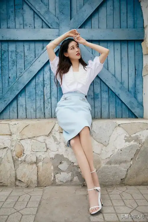 祝绪丹长发飘飘,身穿白色娃娃领中袖上衣搭配蓝色半裙