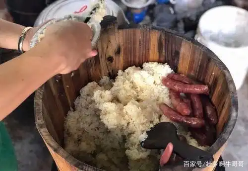 蒸好的糯米饭装在木桶里面,上面还有香肠,香肠的油汁流到糯米饭里