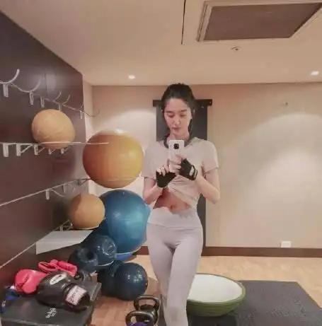 在照片中,杨采钰穿着灰色运动背心和黑色健身裤,可以踩在运动裤上.