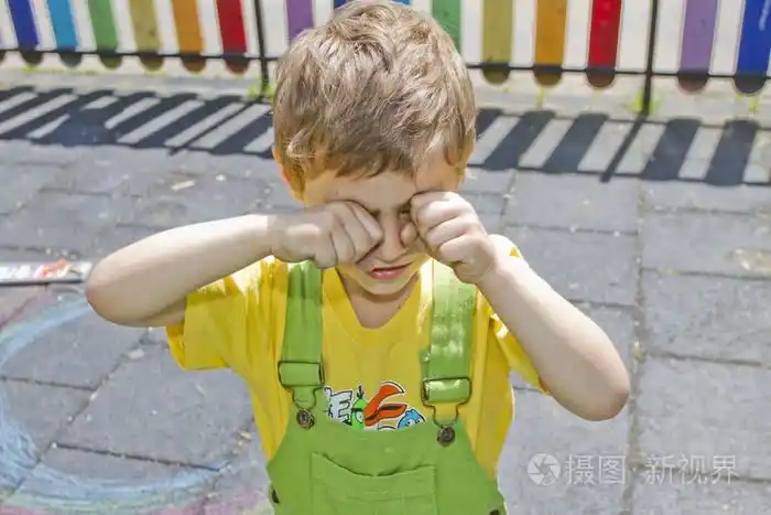 可爱的男孩哭了. 孩子在操场上哭. 一个孩子揉了揉眼睛.