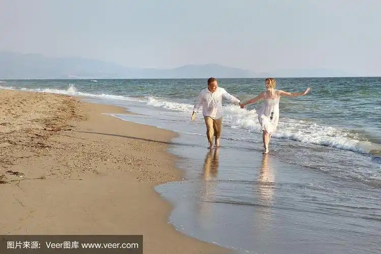 一对情侣在海边的沙滩上手拉手散步