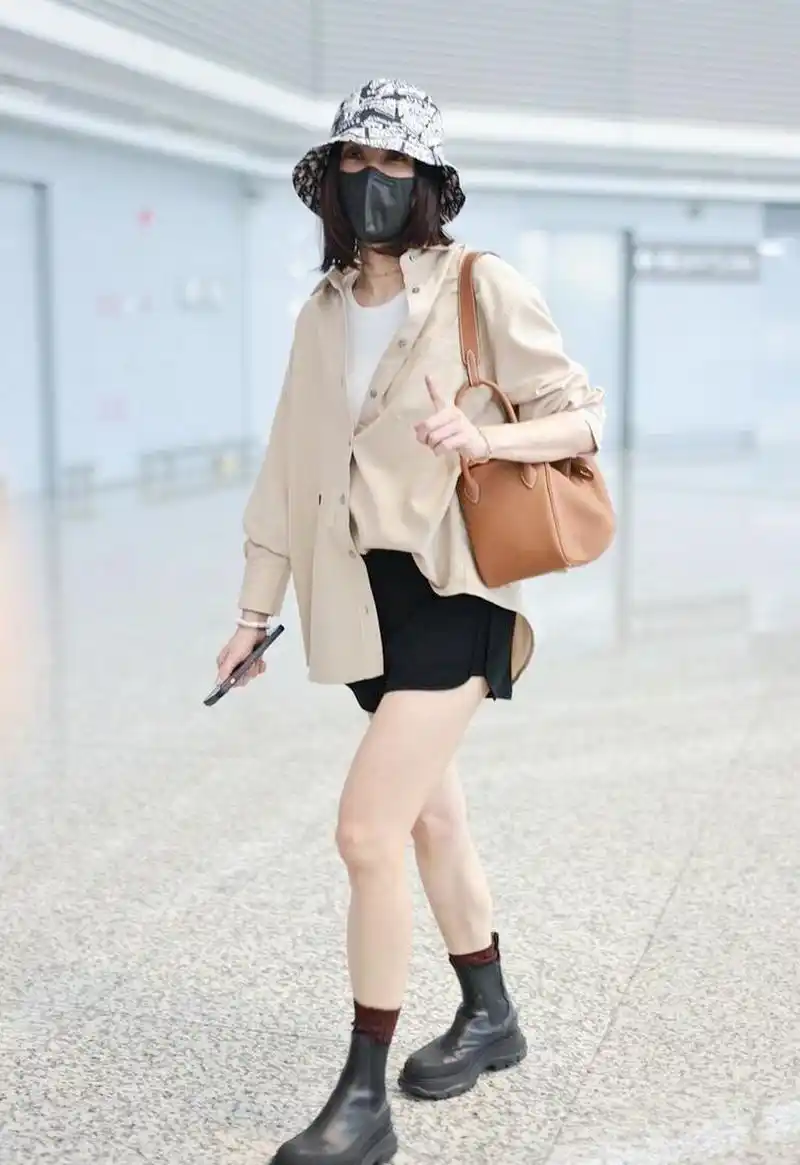 贾静雯机场街拍,卡其色衬衫配白衬衫,黑色短裤 短靴减龄!