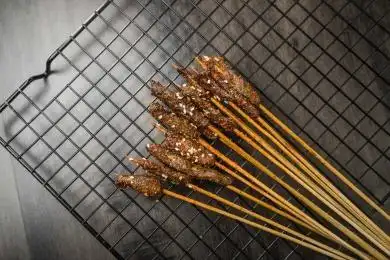 黑色烤架上放着几串撒着辣椒面的油炸牛肉小串