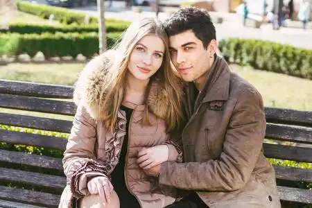 年轻的多种族夫妇,男女异性恋学生恋爱.在城市公园的木凳上约会.