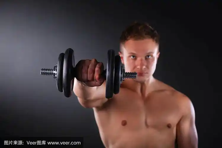 英俊的肌肉男用哑铃健身