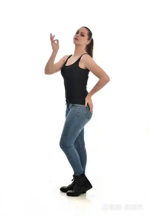 穿黑色单身牛仔裤的黑发女孩的全长肖像站立姿势侧轮