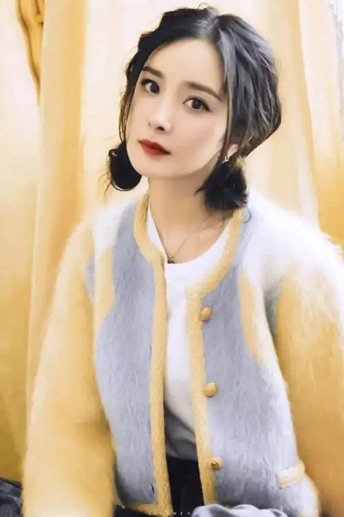 从照片中,只见杨幂上身搭配的是一件短款拼色毛呢外套,搭配双丸子头