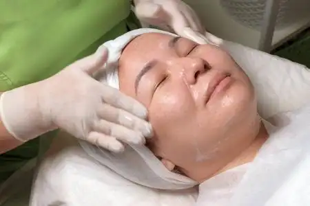 快乐美丽的东方女孩在深层清洁皮肤的过程中.