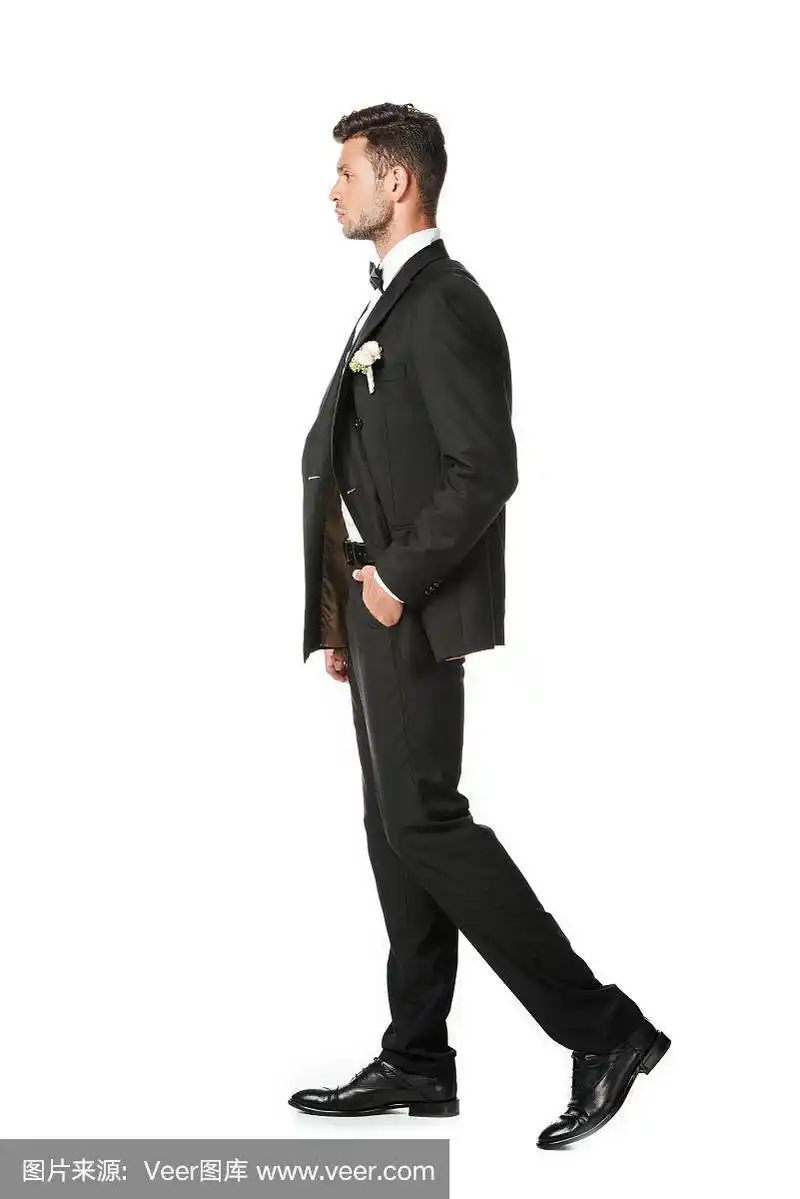 侧面的英俊年轻的新郎在时尚的西装孤立在白色