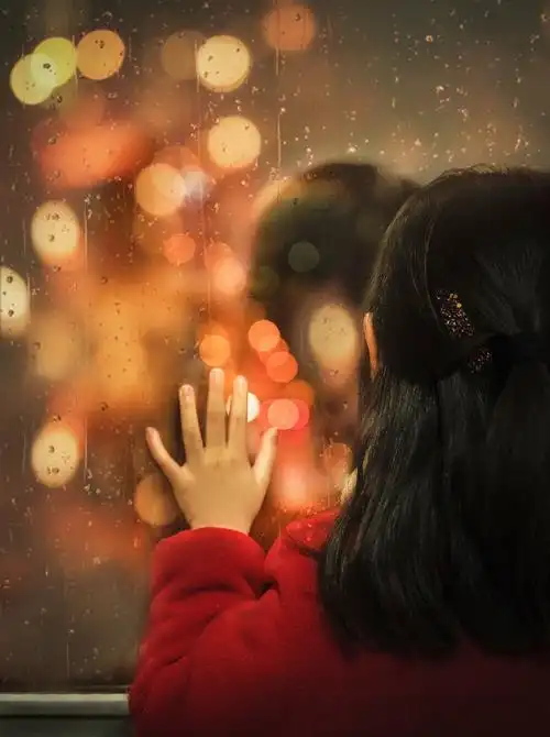 疫情之下待在家里的孩子望着窗外的灯光仿佛那是一颗颗彩虹糖