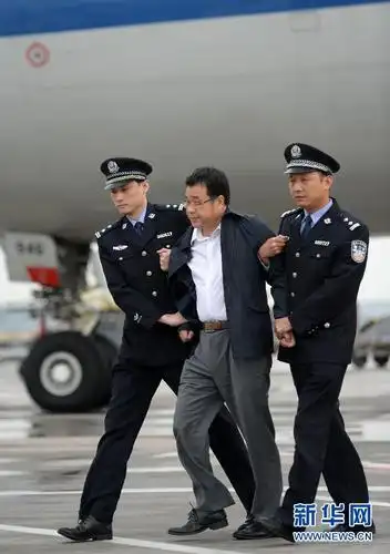 5月9日,在北京首都国际机场,公安干警给李华波(中)戴上手铐.