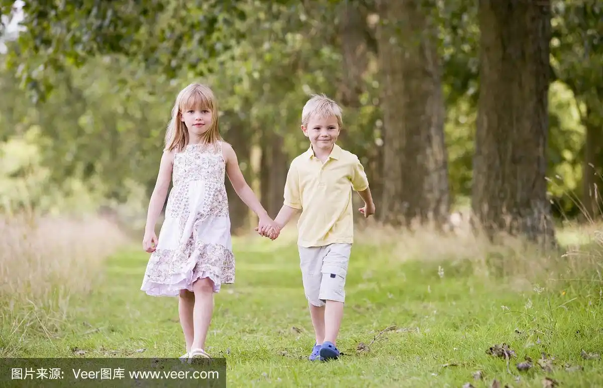 两个小孩手牵着手走在小路上