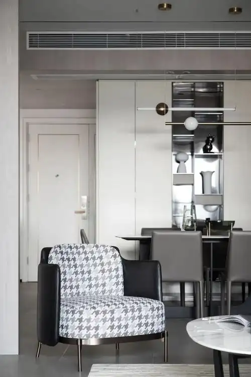 坐感舒适的深灰色l型真皮沙发,搭配浅灰色窗帘和浅灰咖色几何图案地毯