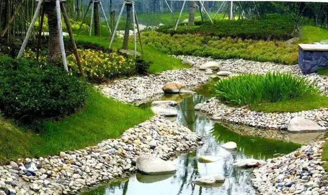 自然式驳岸适当运用块石,鹅卵石,木桩等材料营造一个岸线曲折,岸坡