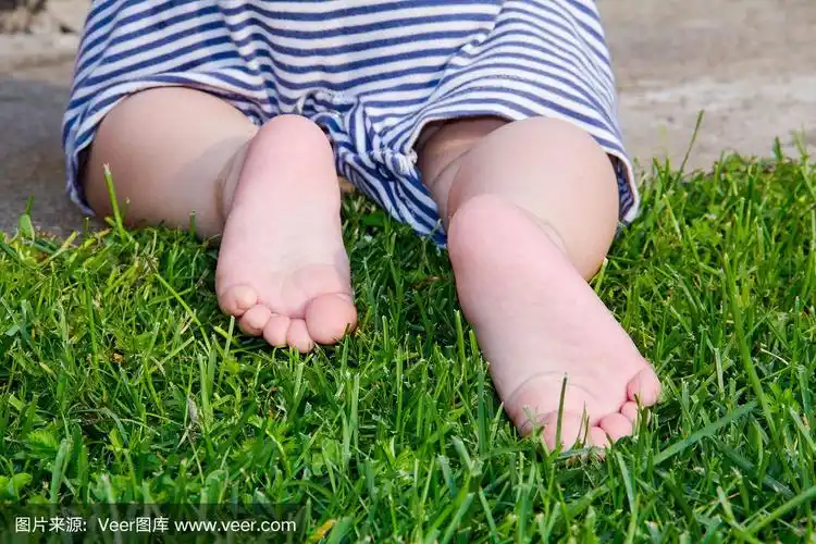 关闭了.快乐的孩子脚赤脚在绿色的草地上