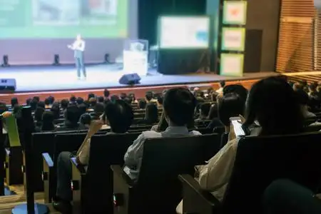 观众的后观在会议厅或研讨会的舞台上聆听演讲者在低光情况下, 商业和