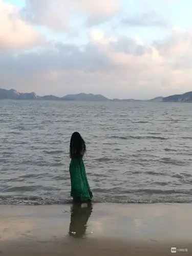 散步时在海边偶遇一长发绿裙女子 背影看起来很孤独.