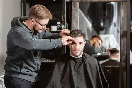 理发师在理发店给男人理发,理发师给年轻人做发型照片
