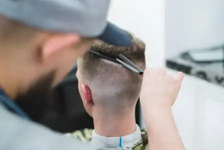理发师用一个年轻人剪她的头发.理发店男士理发照片