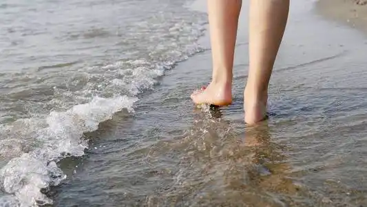 水上行走在赤脚的女性脚下行走,溅在海水上,电影中的稳定镜头照片